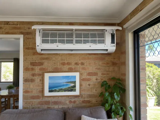 Clean split system indoor unit with open front panel on a brick wall in a living room in Highland Park